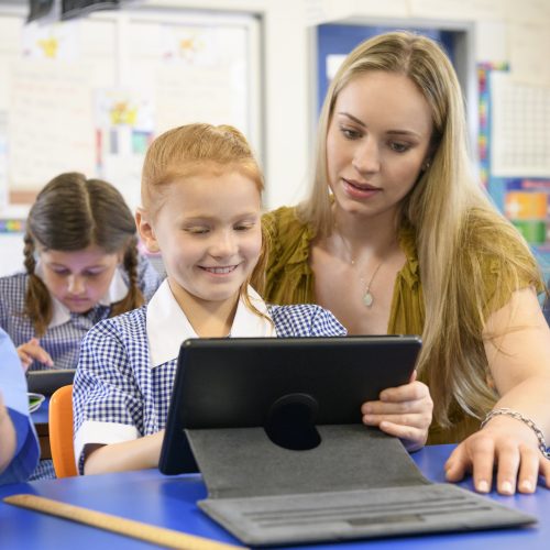 An image of an education support worker helping a young student with his homework
